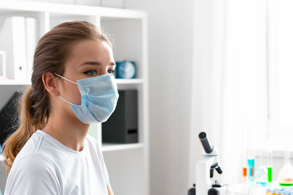 Женщина в медицинской маске сидит в кабинете врача - Фото, изображение