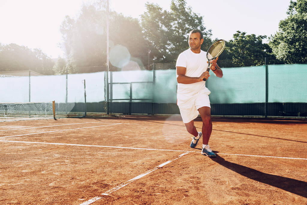 Fitter Mann spielt Tennis auf dem Tennisplatz - Foto, Bild