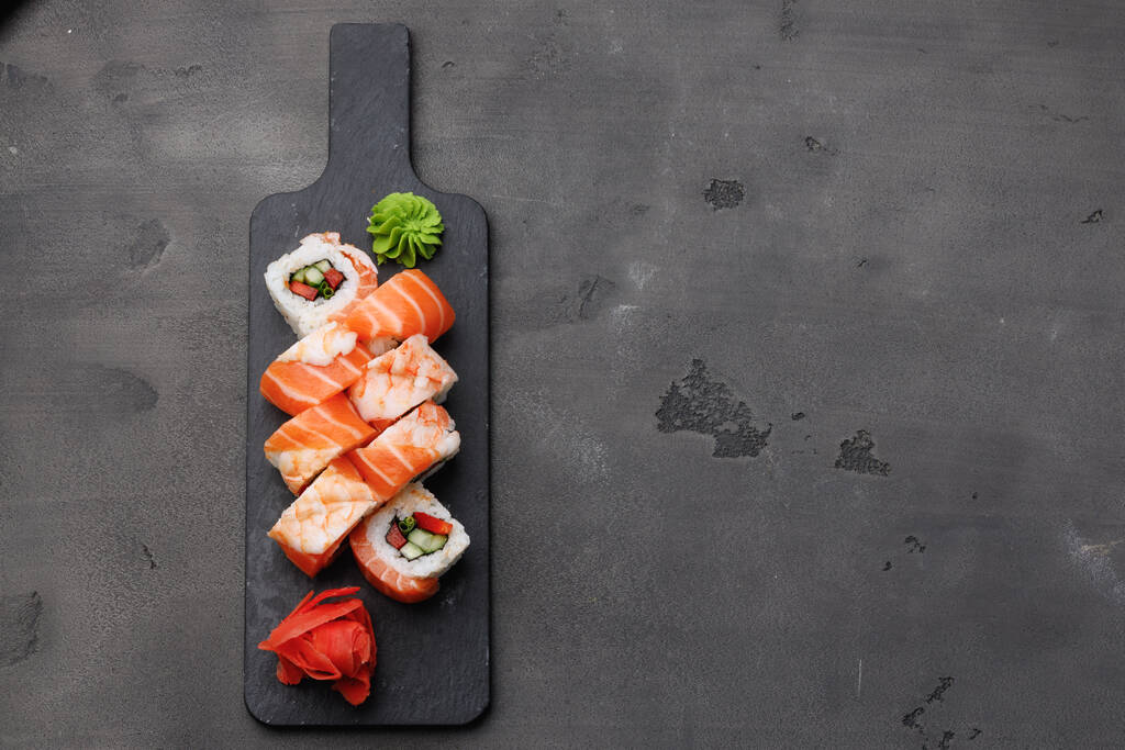Top view of sushi roll with salmon and crewn on black background - Фото, изображение