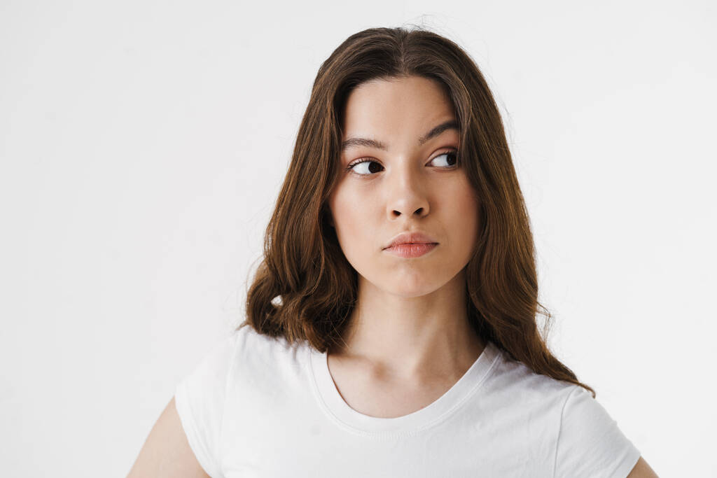 Pensive jonge vrouw denken geïsoleerd over witte achtergrond - Foto, afbeelding