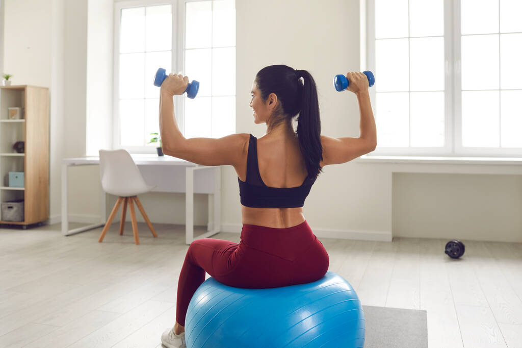 Улыбаясь довольно молодой фитнес стройная женщина в спортивной одежде делает тренировку на фитнес-мяч - Фото, изображение
