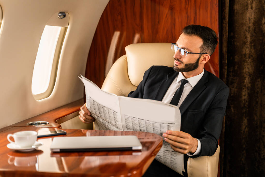 Красивый бизнесмен в элегантном костюме, летящий на эксклюзивном частном самолете - успешный предприниматель, сидящий в эксклюзивном бизнес-классе на самолете, концепции о бизнесе и trasportation - Фото, изображение