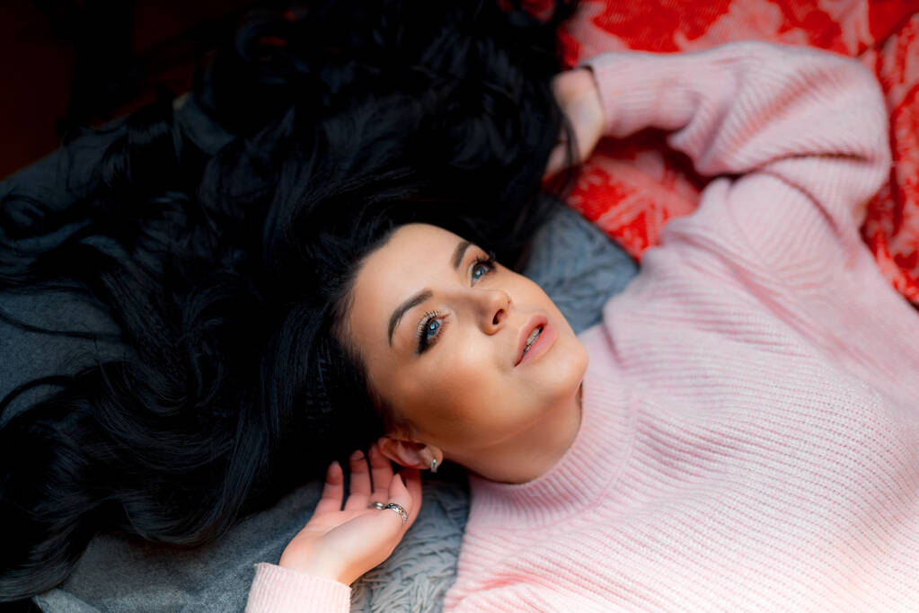 Retrato de uma mulher de cabelos escuros atraente com cabelo comprido deitado em uma cama. Tiro de cima. - Foto, Imagem