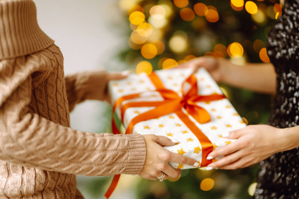 Gives the gift. Exchanging the christmas presen. Young woman gives a gift in a box. Winter holiday, New Year, celebration, birthday concept. - Photo, Image
