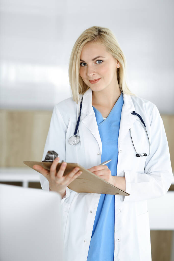 Žena-doktorka stojící v nemocnici nebo na klinice a vyplňující záznamy o lécích. Data a nejlepší služby v medicíně a zdravotnictví - Fotografie, Obrázek