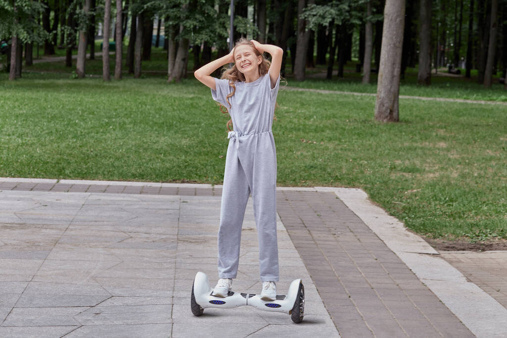 Mooi gelukkig meisje in wit sneakers op een gyro scooter, hoverboard. - Foto, afbeelding