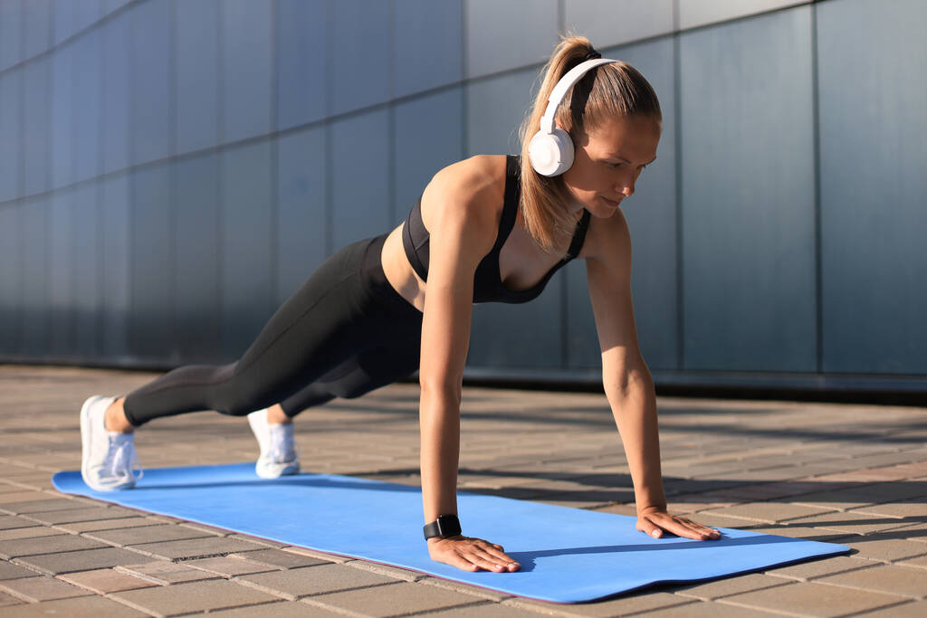 Deporte chica haciendo ejercicio tablón al aire libre en cálido día de verano
 - Foto, Imagen