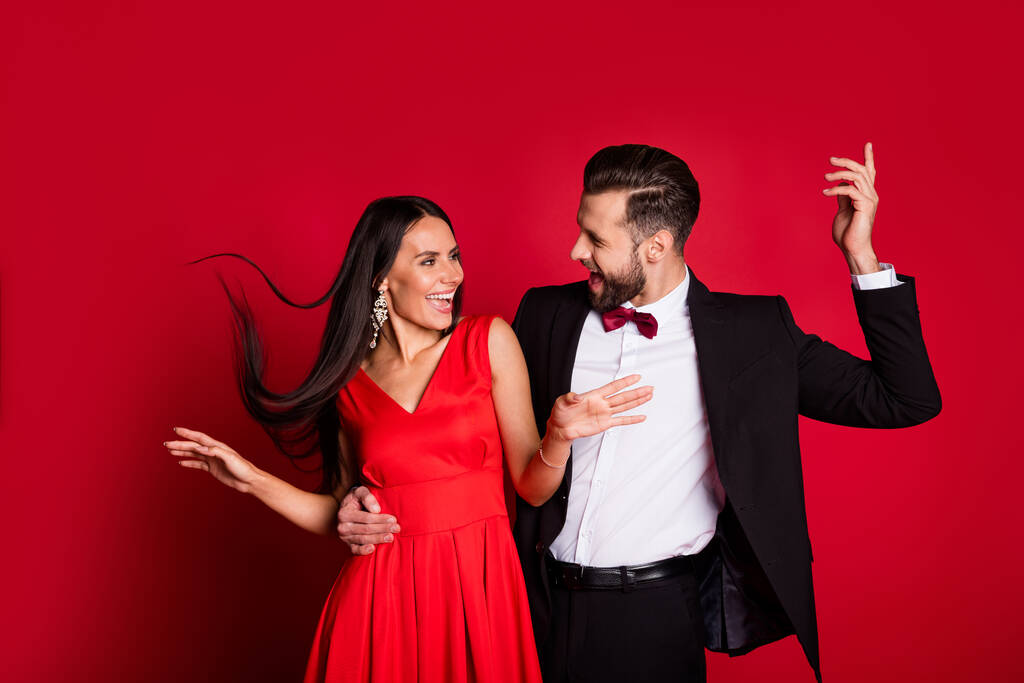 Foto de divertida pareja optimista bailando traje de vestir aislado sobre fondo de color rojo - Foto, Imagen
