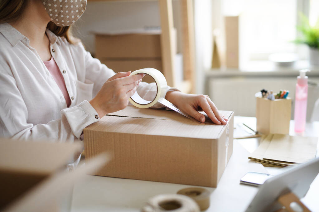 Unrecognizable woman dropshipper working at home, packing parcels. Coronavirus concept. - Photo, Image