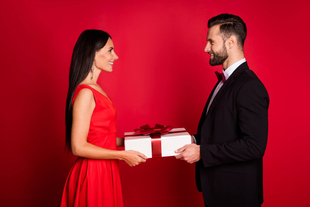 素敵な楽観的なカップルのプロフィール写真を与える現在の着用スーツドレス隔離された赤の色の背景 - 写真・画像