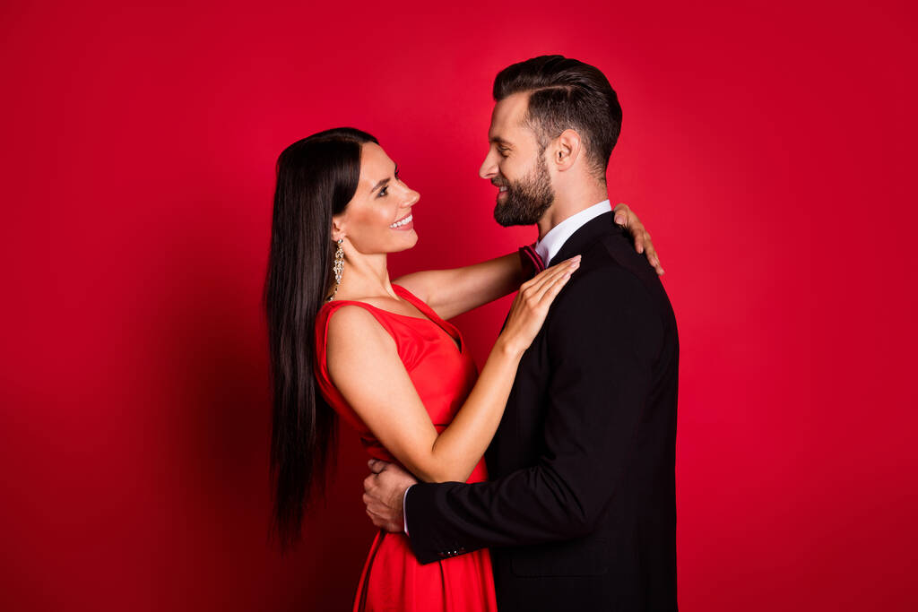 Φωτογραφία προφίλ του αισιόδοξου χαριτωμένο ζευγάρι φόρεμα φορούν κοστούμι απομονωμένο σε φόντο κόκκινο χρώμα - Φωτογραφία, εικόνα