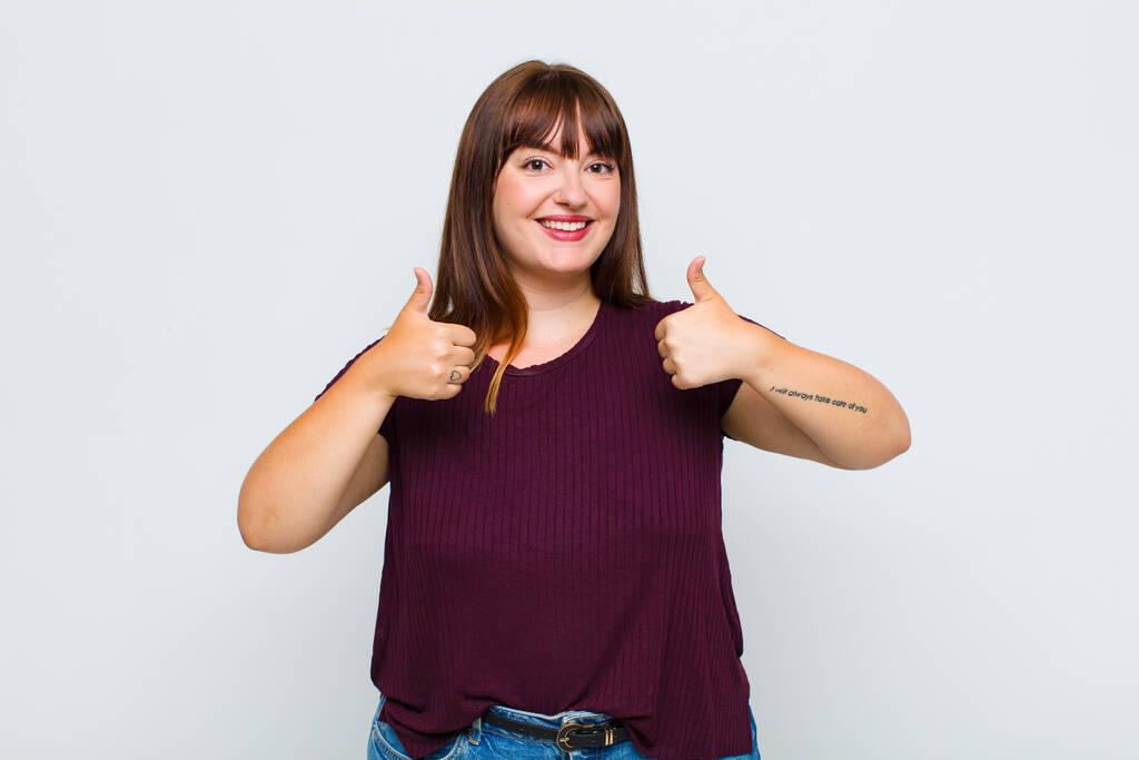 mulher com sobrepeso sorrindo amplamente olhando feliz, positivo, confiante e bem sucedido, com ambos os polegares para cima - Foto, Imagem