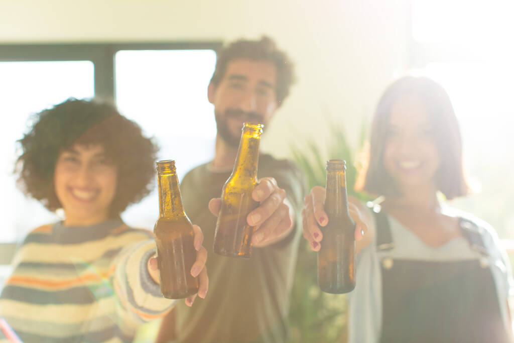 Gruppe von Freunden trinkt Bier, entspannt und glücklich im neuen Zuhause - Foto, Bild