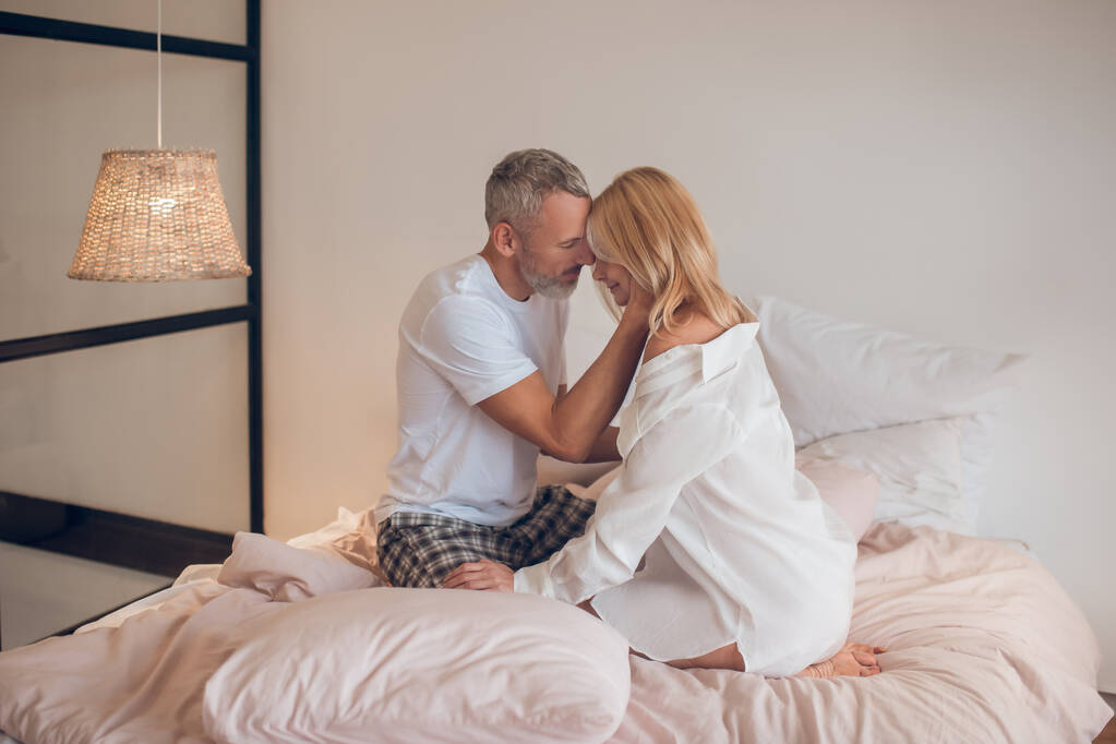 baard man knuffelen een blonde vrouw en op zoek romantisch - Foto, afbeelding
