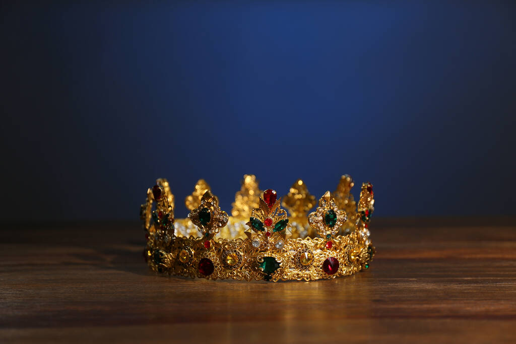 Beautiful golden crown with gems on wooden table. Fantasy item - Photo, Image