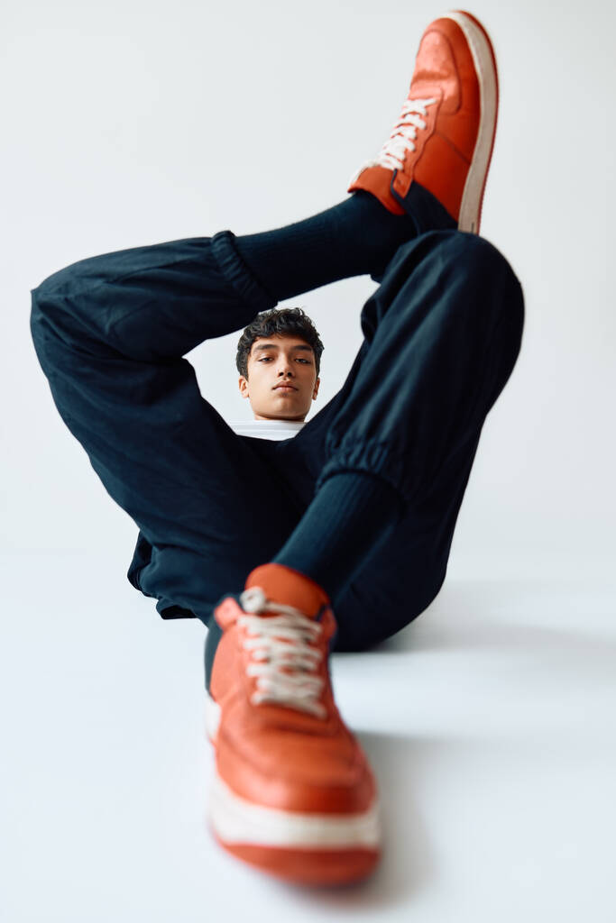 Joven hombre de moda de raza mixta posando en el estudio tumbado en el suelo sobre fondo blanco - Foto, imagen