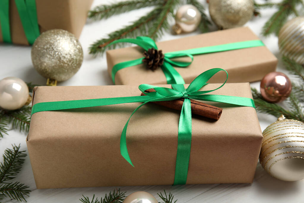 Dárková krabička se zelenou stuhou a vánoční výzdobou na bílém dřevěném stole, detailní záběr - Fotografie, Obrázek