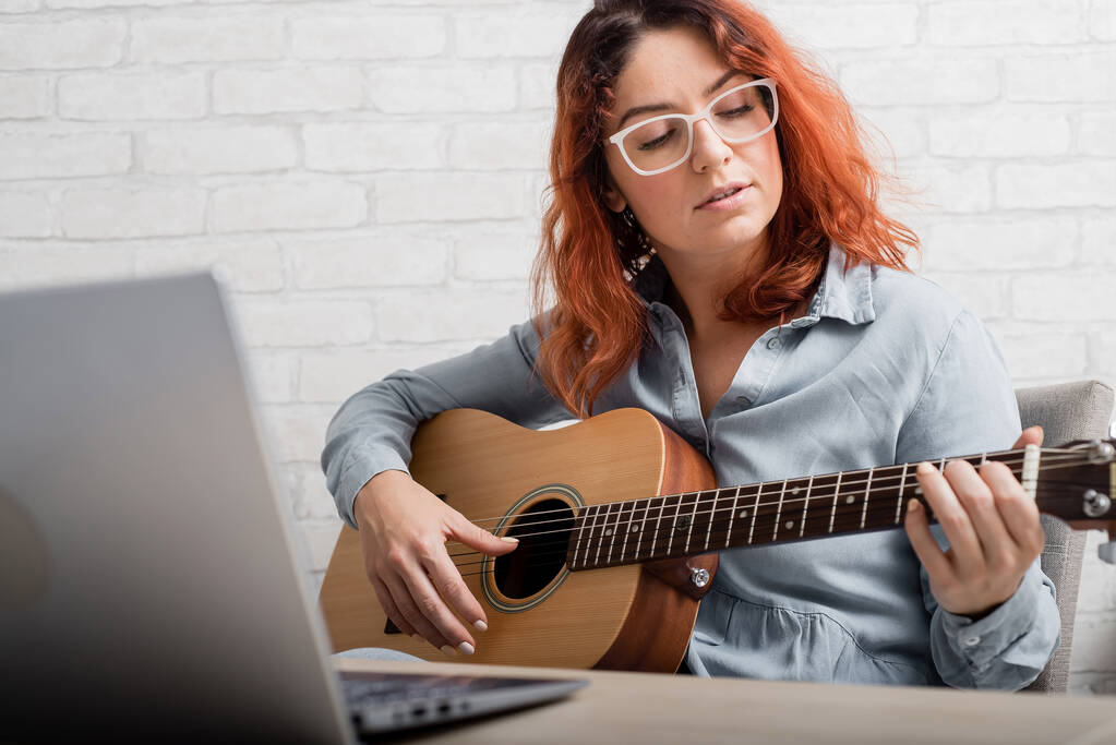 白人女性はオンラインでギターを学ぶ。少女は音楽を遠隔で研究隔離されている - 写真・画像