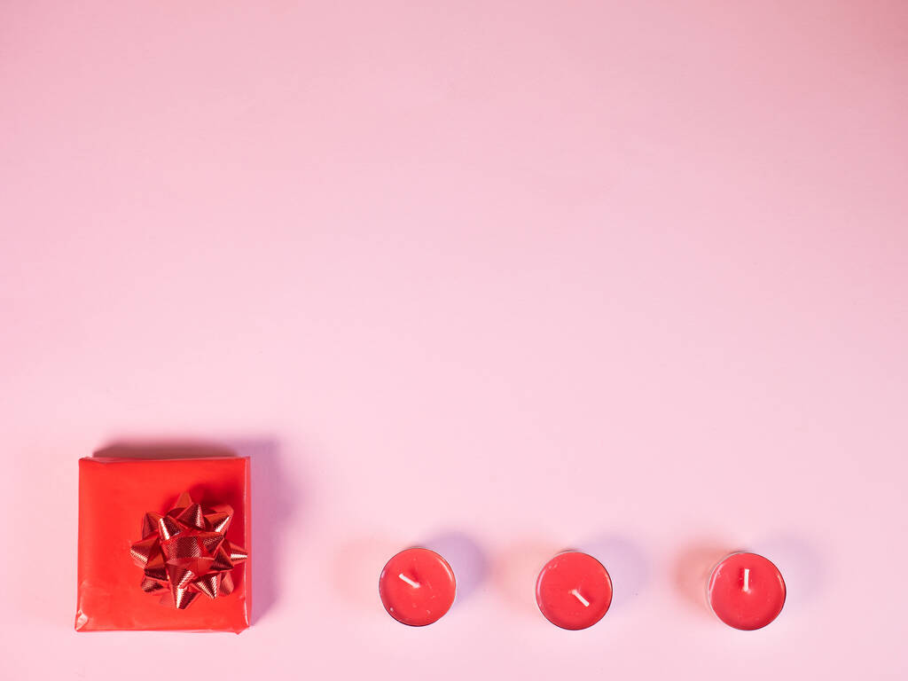 Caja de regalo roja con velas sobre fondo rosa - Foto, imagen
