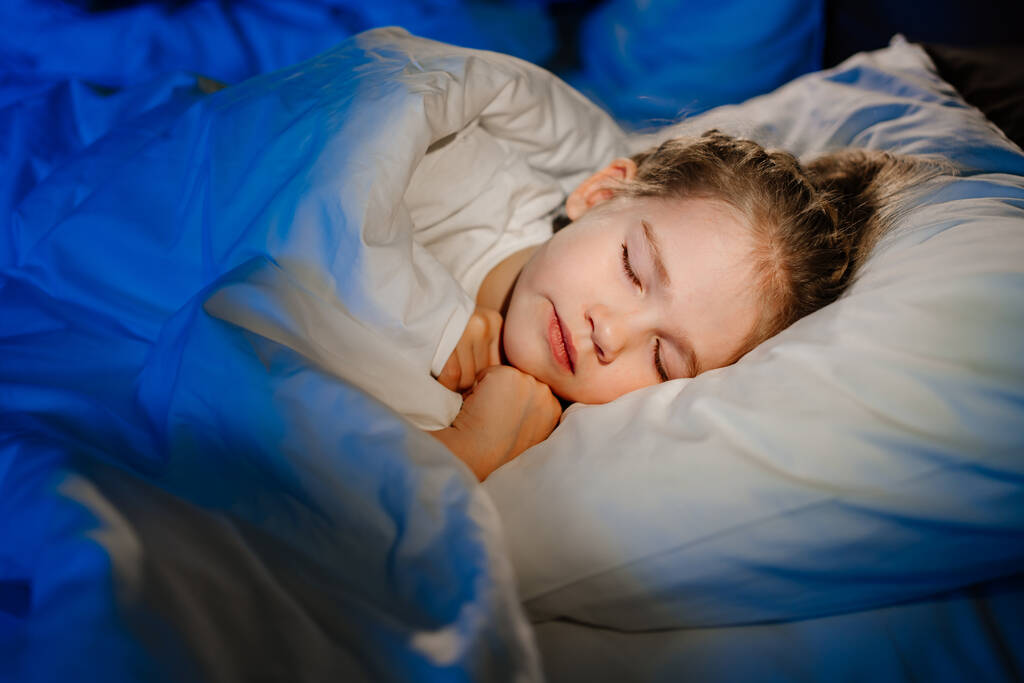une jolie petite fille dort dans un lit. sommeil calme et sain des enfants.  - Photo, image