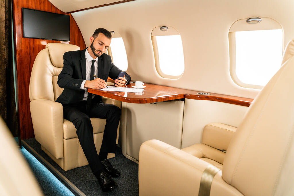 Красивий бізнесмен в елегантному костюмі, що летить на ексклюзивному приватному літаку - успішний підприємець, сидячи в ексклюзивному бізнес-класі на літаку, концепції про бізнес і транспортування
 - Фото, зображення