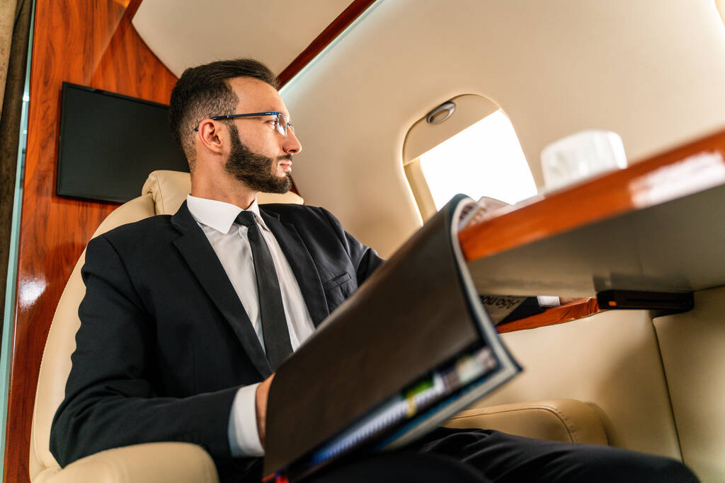 Komea liikemies yllään tyylikäs puku lentävät yksinoikeudella yksityinen suihkukone Onnistunut yrittäjä istuu yksinoikeudella business class lentokoneessa, käsitteitä liiketoiminnan ja trasportation - Valokuva, kuva