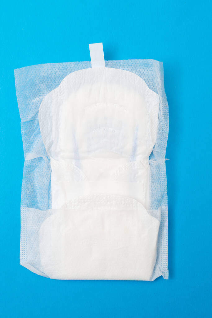Almofada feminina sobre fundo azul. Produto de higiene para menstruação. - Foto, Imagem