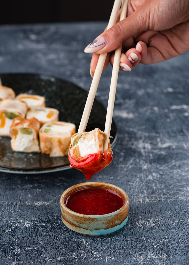 Postre tradicional japonés, dulce rollo, cubierto con mermelada de fresa roja con palillos vista desde la parte superior, postre de sushi dulce con mermelada de fresa - Foto, Imagen