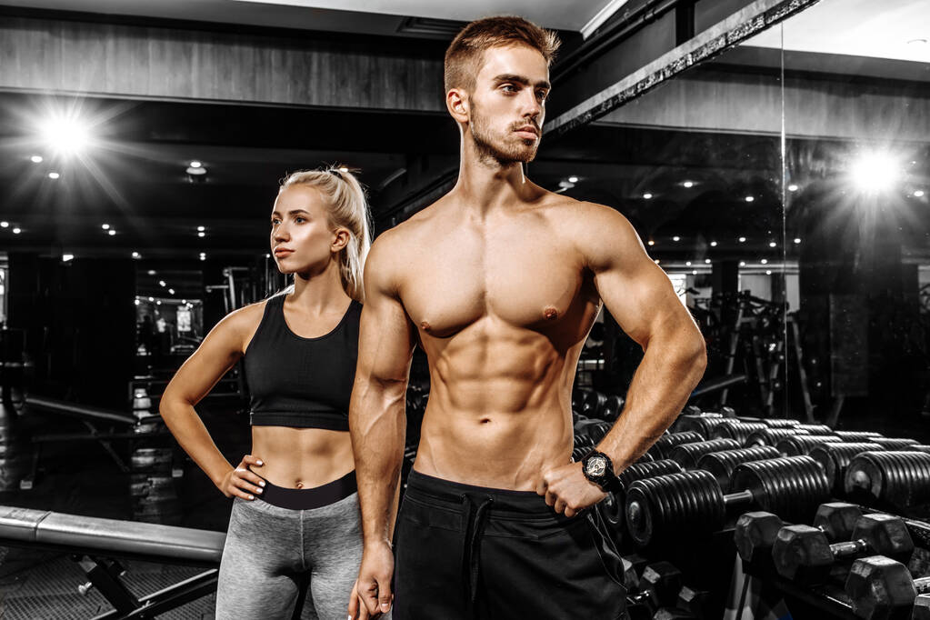 Αθλητικό νεαρό ζευγάρι, άνδρας και γυναίκα σε αθλητικά είδη, στο γυμναστήριο - Φωτογραφία, εικόνα