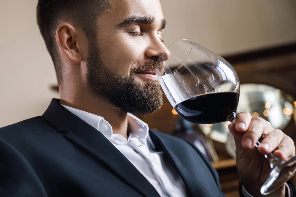 Portrait d'un bel homme barbu avec un verre de vin rouge - Photo, image