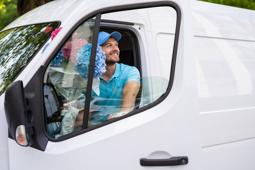 Glücklicher Kurier im weißen Lieferwagen bei der Blumenübergabe wartet auf einen Kunden - Foto, Bild