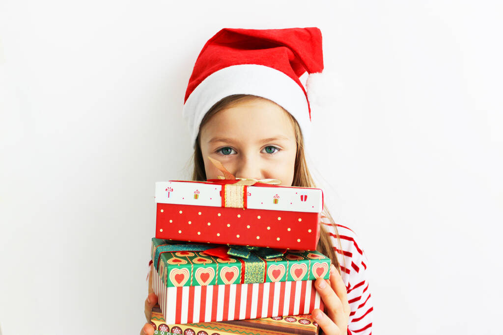 Piękna dziewczyna czerwony sweter Boże Narodzenie i Nowy Rok prezent. Happy little girl w Santa s kapelusz ma Boże Narodzenie. - Zdjęcie, obraz