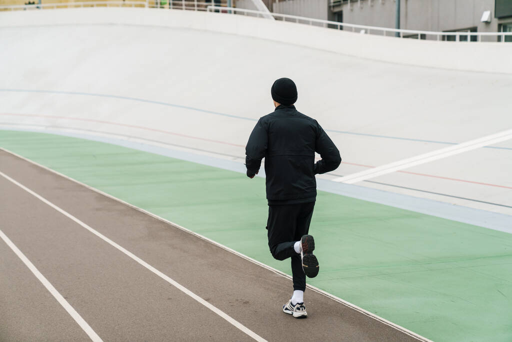 Αθλητικός αθλητής τρέχει ενώ εργάζονται έξω στο γήπεδο σε εξωτερικούς χώρους - Φωτογραφία, εικόνα