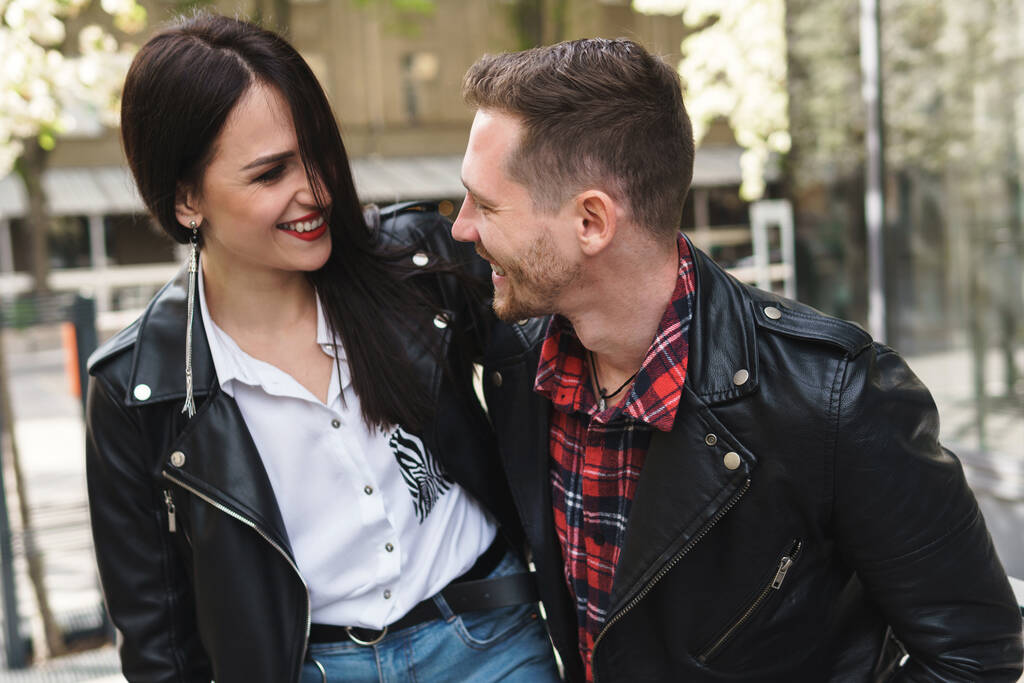 若い陽気なカップルは、屋外でのデート中に革のジャケットを着て - 写真・画像