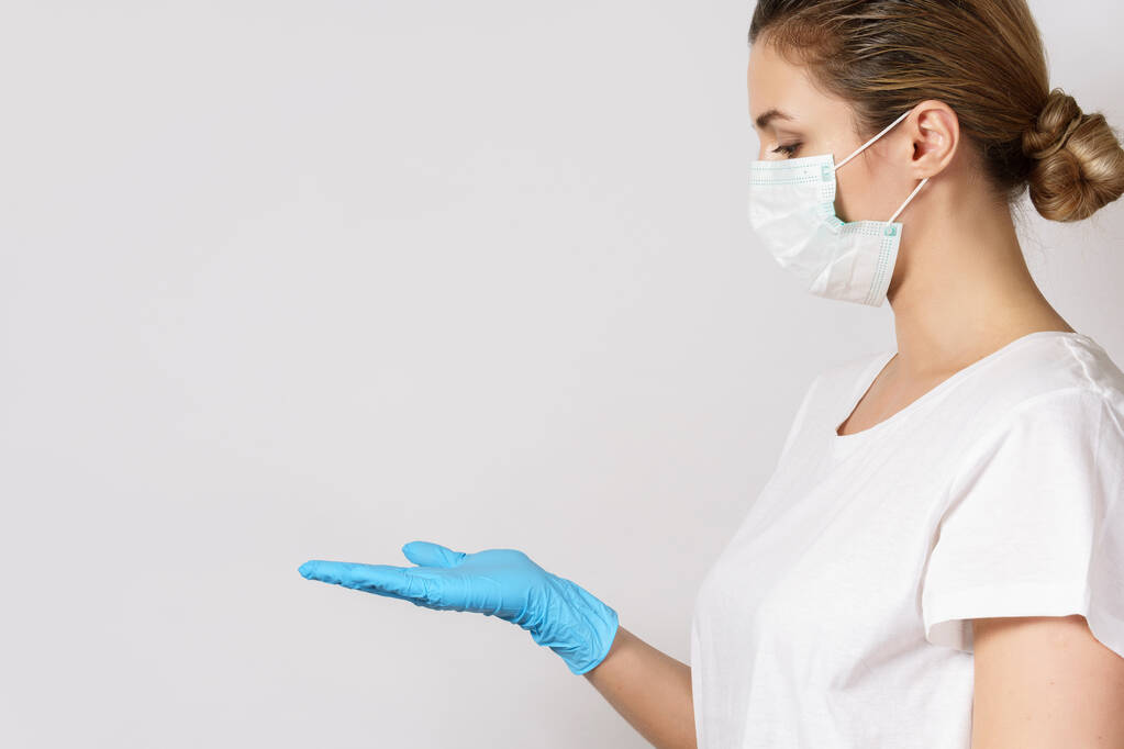 Mujer caucásica joven está usando una máscara facial y guantes de látex para la protección contra el virus - Foto, imagen