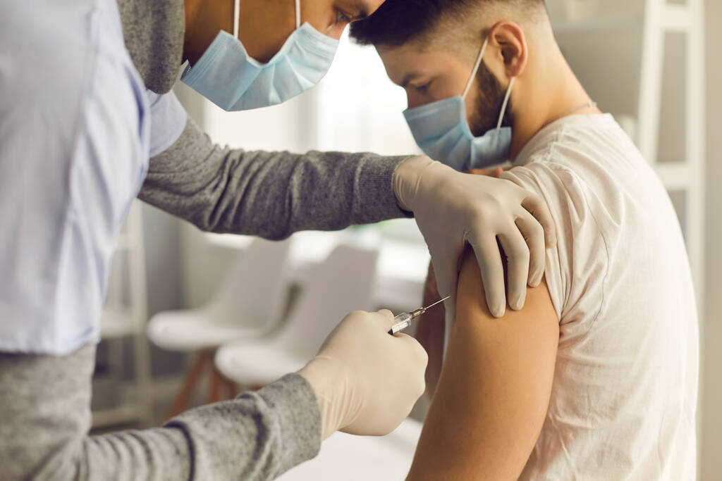Доктор вводить пацієнта з противірусною вакциною під час кампанії масової вакцинації
 - Фото, зображення
