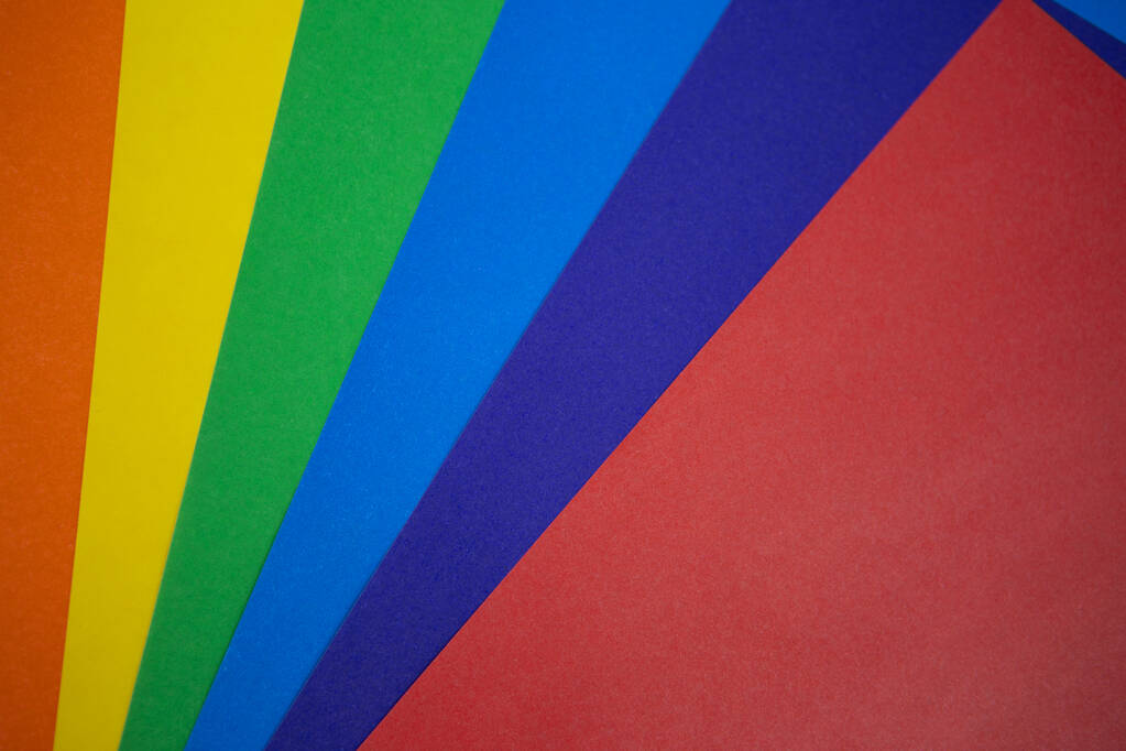 The background texture of colored paper is spread out in a color spectrum like a rainbow: from shades of orange, yellow, green, blue, blue, red at the end. Photo from the top - Photo, Image