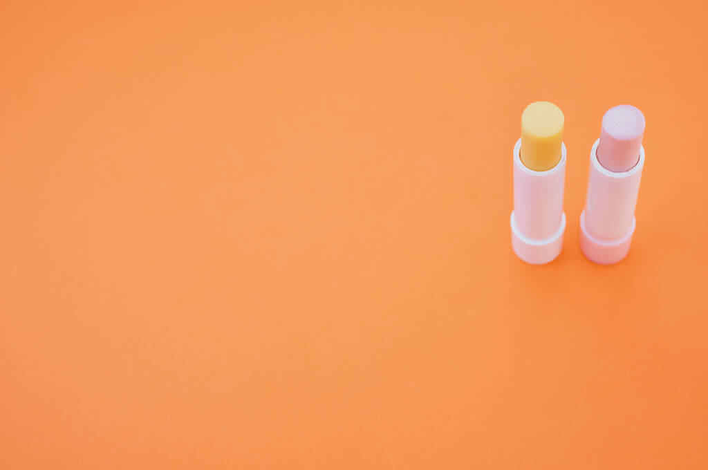 Un primer plano de lápiz labial higiénico aislado sobre fondo naranja - Foto, Imagen