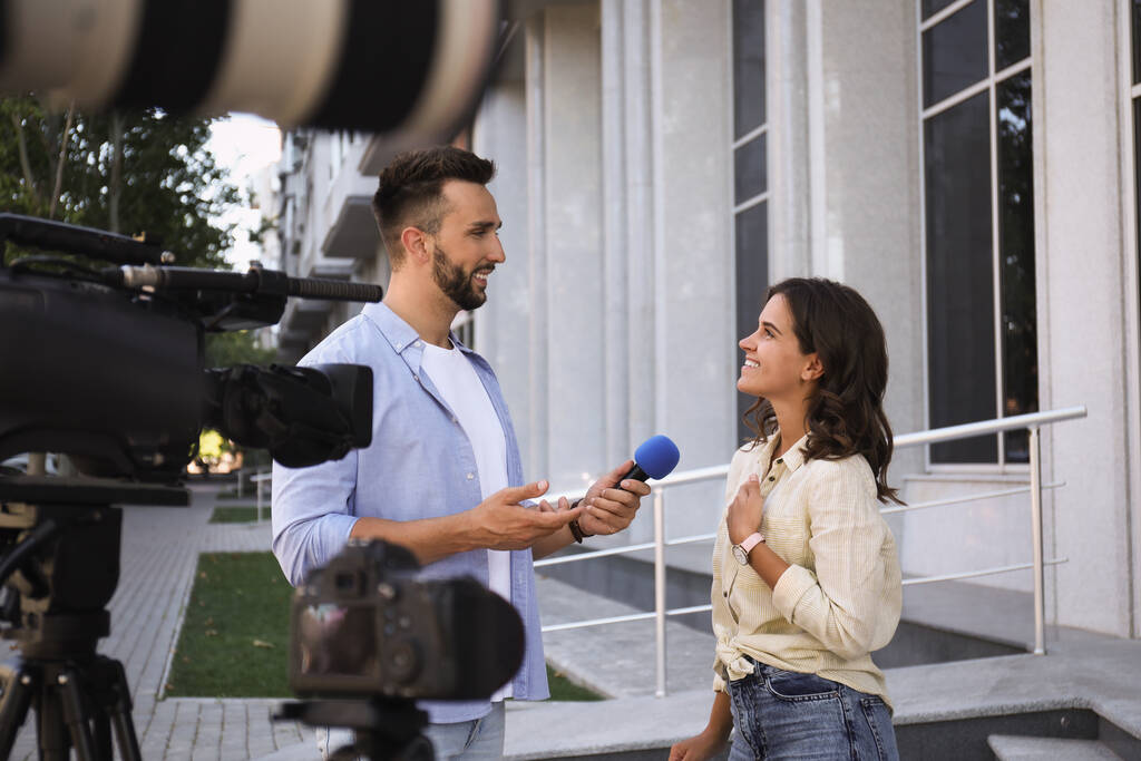 Journaliste professionnel prenant interview devant des caméras vidéo en plein air - Photo, image