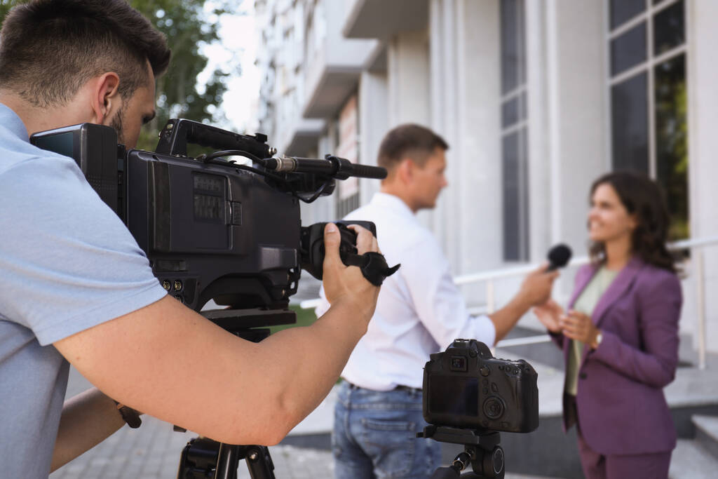 Επαγγελματίας δημοσιογράφος και χειριστής με βιντεοκάμερα που παίρνει συνέντευξη σε εξωτερικούς χώρους - Φωτογραφία, εικόνα