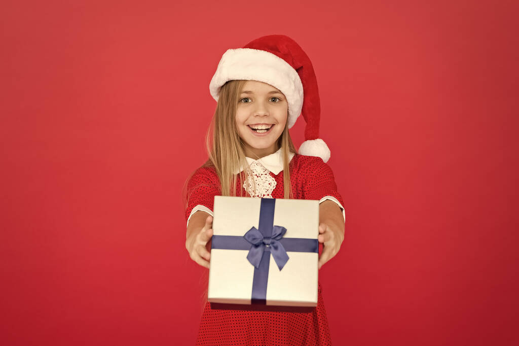 Веселий дитячий карнавальний костюм червоний фон. Сюрприз для неї. Щасливі зимові свята. Маленька дівчинка відкриває подарунок. Новий рік. Подарунок Санта-Клаусу. Маленька дівчинка отримала подарунок. Справжнє Різдво. Чарівний момент
 - Фото, зображення