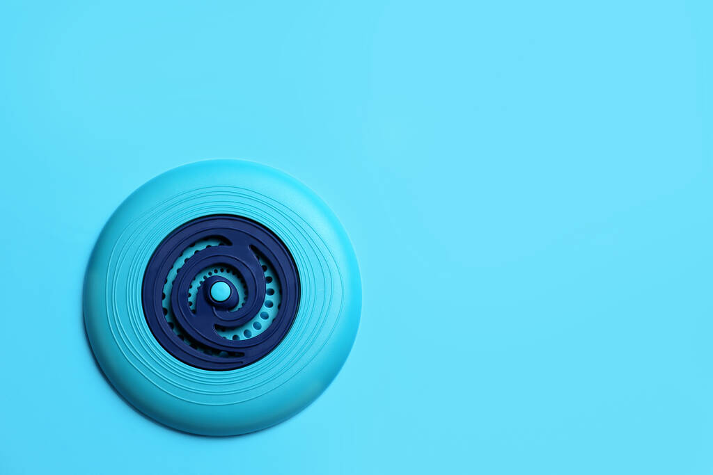 Plastikowy dysk frisbee na jasnoniebieskim tle, widok z góry. Miejsce na tekst - Zdjęcie, obraz