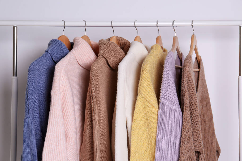 Warm sweaters hanging on rack against white background - Photo, Image