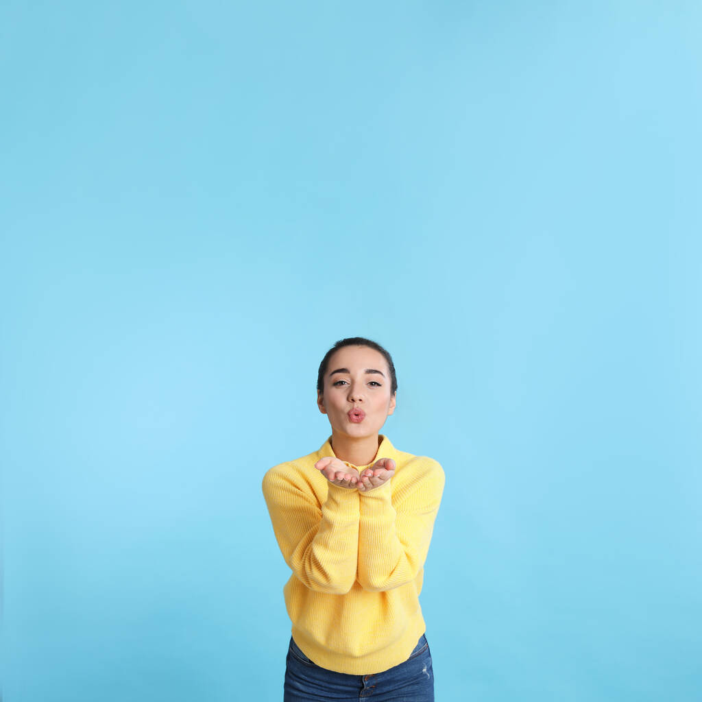 Schöne junge Frau in gelbem warmen Pullover auf hellblauem Hintergrund. Raum für Text - Foto, Bild