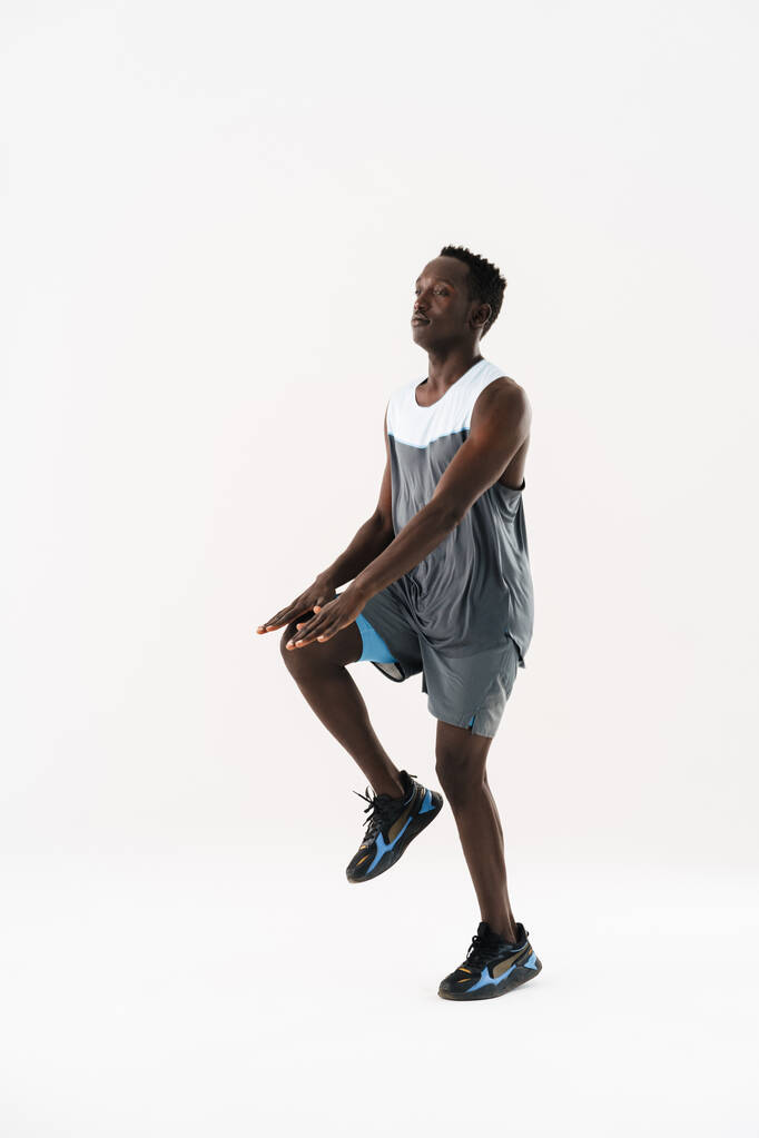 Nuori afrikkalainen amerikkalainen urheilija tekee liikuntaa työskennellessään eristetty valkoisella taustalla - Valokuva, kuva