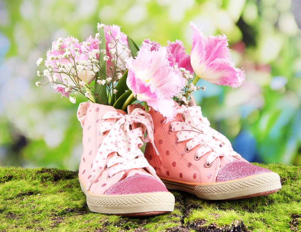 mooie gumshoes met bloemen binnen op groen gras, op lichte achtergrond - Foto, afbeelding