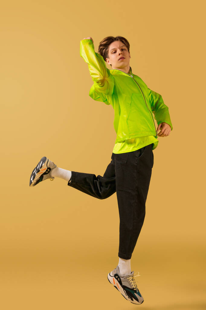 Παλιομοδίτης νεαρός που χορεύει απομονωμένος σε κίτρινο φόντο - Φωτογραφία, εικόνα