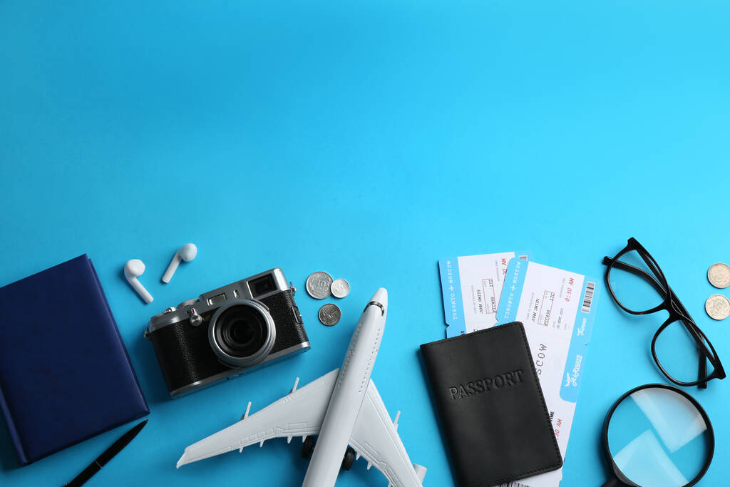 Плоская композиция с игрушечным самолетом и туристическими предметами на светло-голубом фоне. Пространство для текста - Фото, изображение