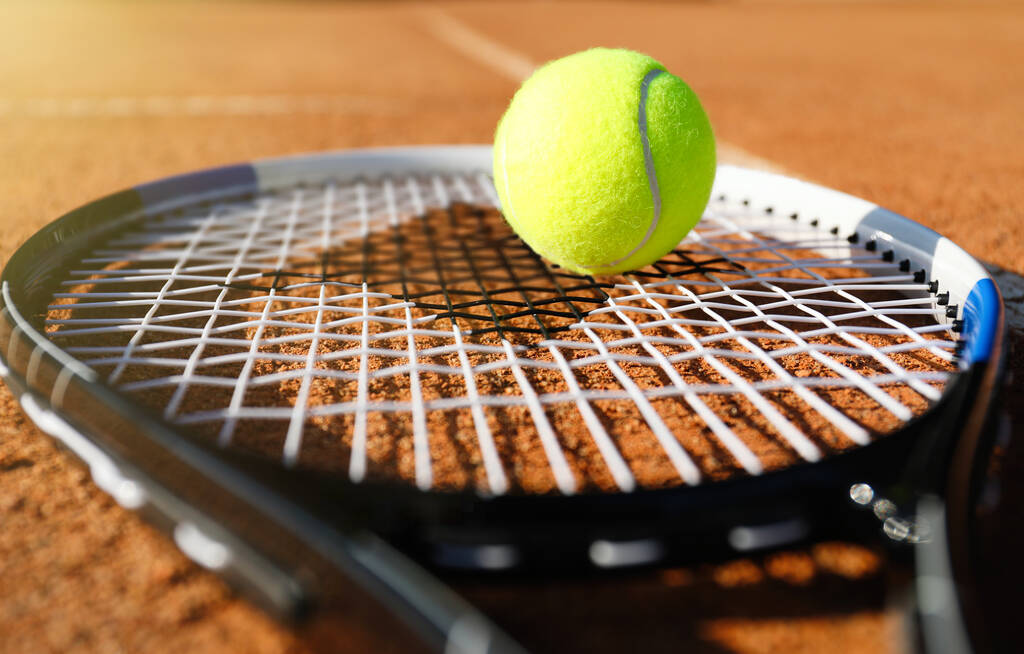 Μπάλα τένις και ρακέτα σε πήλινο γήπεδο, κοντινό πλάνο - Φωτογραφία, εικόνα