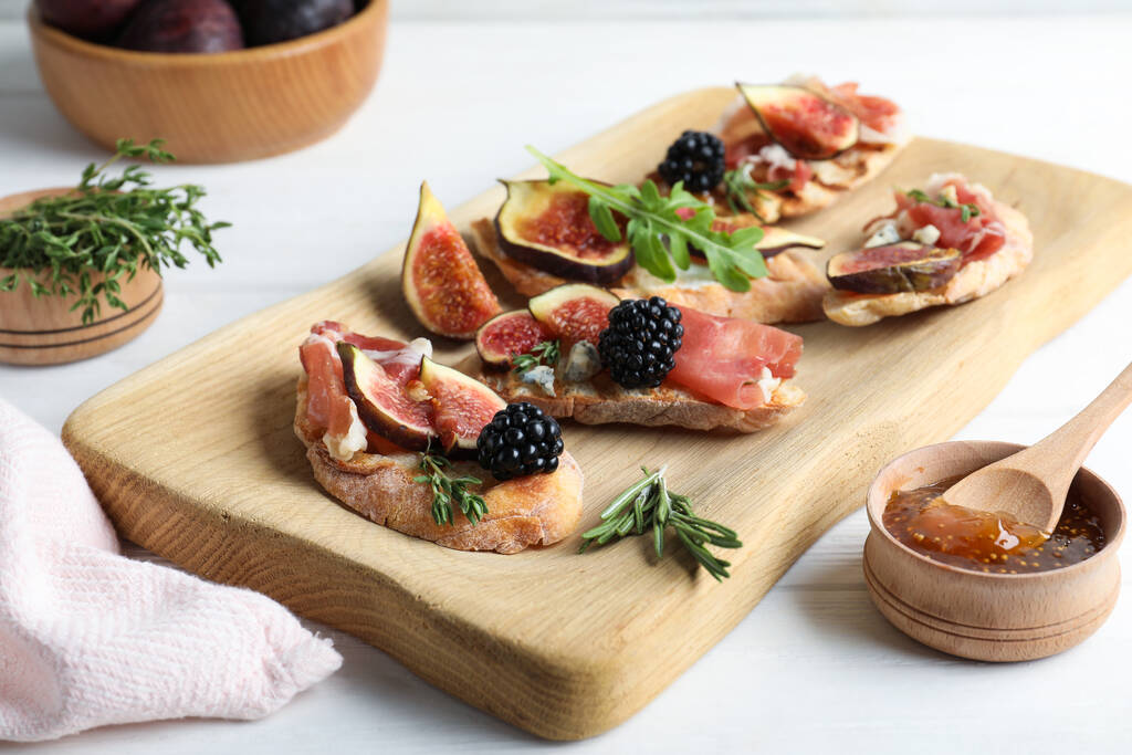 Sandwiches with ripe figs and prosciutto served on white wooden table - Photo, Image